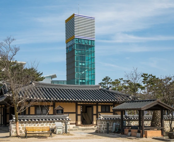 전통 기와집 뒤로 유리로 된 전망 타워가 솟아 있는 속초시립박물관 일대 풍경