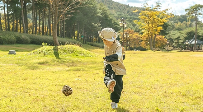 해설사 선생님이 던진 칡공을 향해 두 아이가 잔디밭을 달려 다가가는 모습