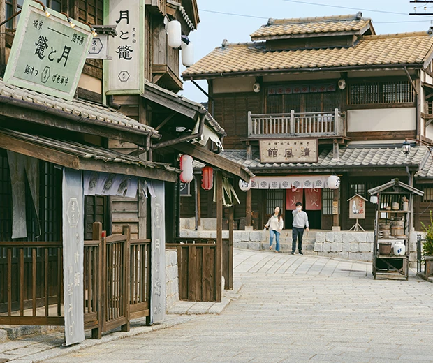 일본식 목조 건물과 한자 간판이 늘어선 거리에 두 사람이 걷는 동매 거리 세트