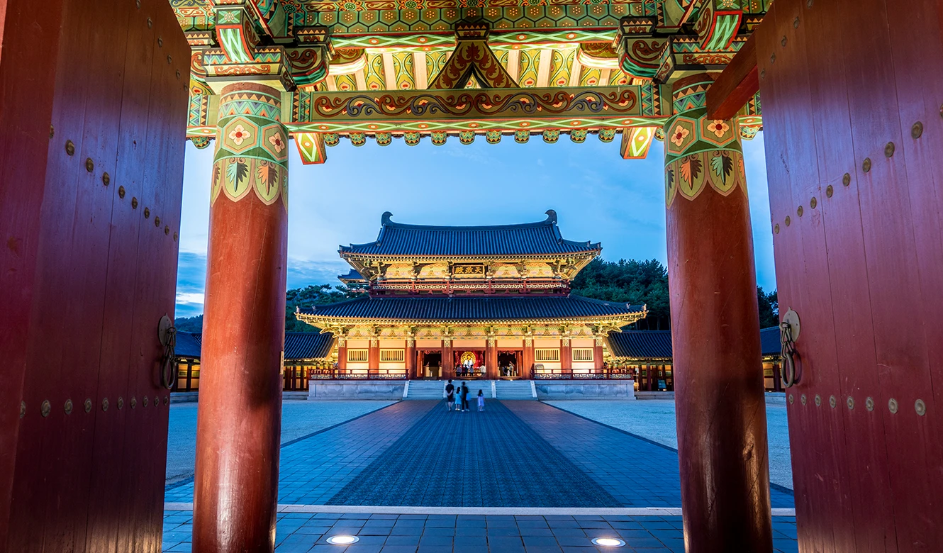 붉은 기둥의 솟을대문 너머로 조명을 환히 밝힌 사비궁 전각이 보이는 야경
