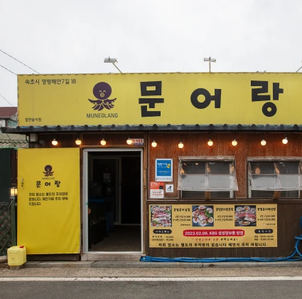 노란 외벽에 큼직한 글씨로 문어랑 간판을 단 해산물 식당의 거리 정면 모습