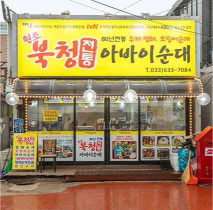 노란 간판이 환한 북청전통아바이순대 가게 외관, 전구로 장식한 입구가 보인다