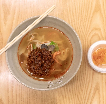 다진 양념을 얹은 마라칼국수 한 그릇과 곁들임 소스를 위에서 내려다본 모습