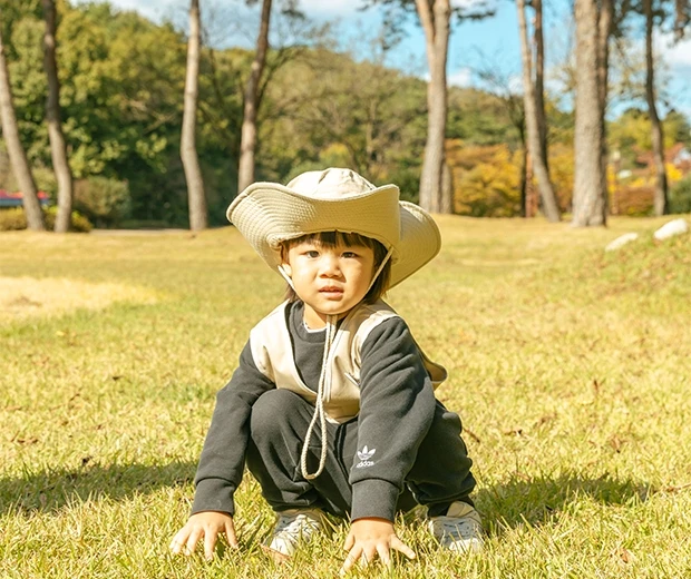 단풍 든 숲을 배경으로 아이가 잔디밭에 서서 가을 자연을 만끽하는 모습