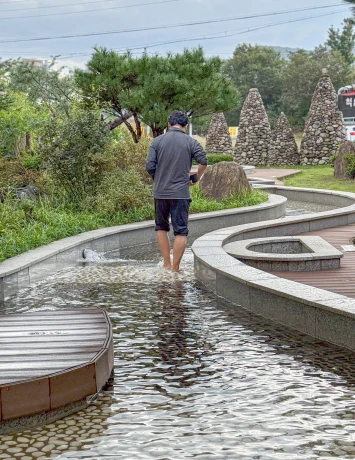 한 남성이 바지를 걷고 곡선형 족욕탕 물길을 따라 걸으며 족욕을 즐기는 모습