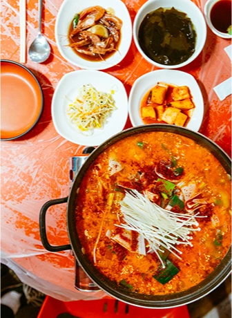 신김치를 넣고 얼큰하게 끓여 채 썬 고명을 올린 붉은 국물의 도치알탕 전골 한 상
