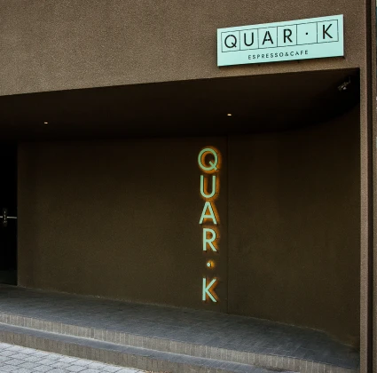 QUAR·K 간판과 세로형 네온사인이 빛나는 어두운 톤의 모던한 카페 쿼크커피바 외관