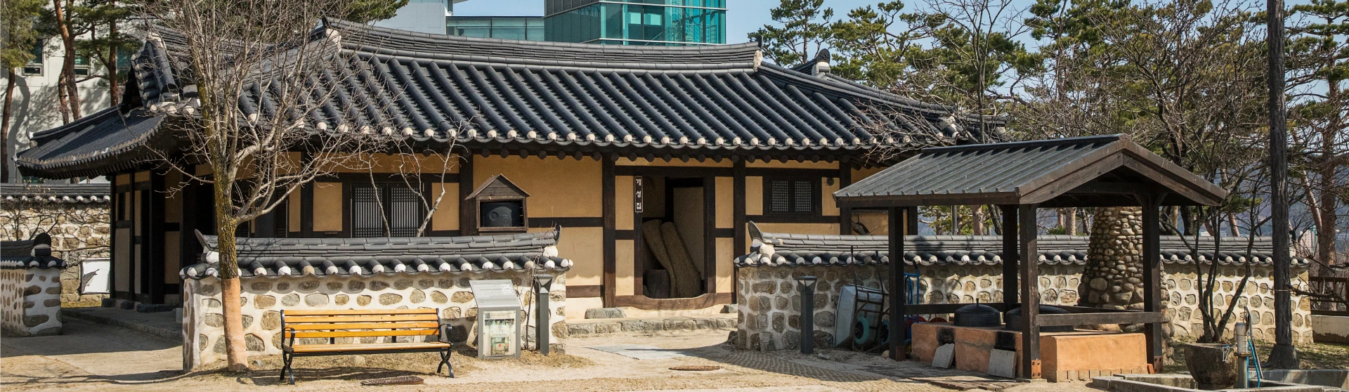 돌담을 두른 전통 기와집과 정자가 자리한 실향민문화촌 외경, 마당 한쪽에 나무 벤치가 놓여 있다