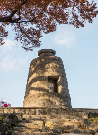 단풍나무 아래 돌을 쌓아 올린 옥녀봉 봉화대와 그 앞 돌계단, 태극기가 함께 보인다