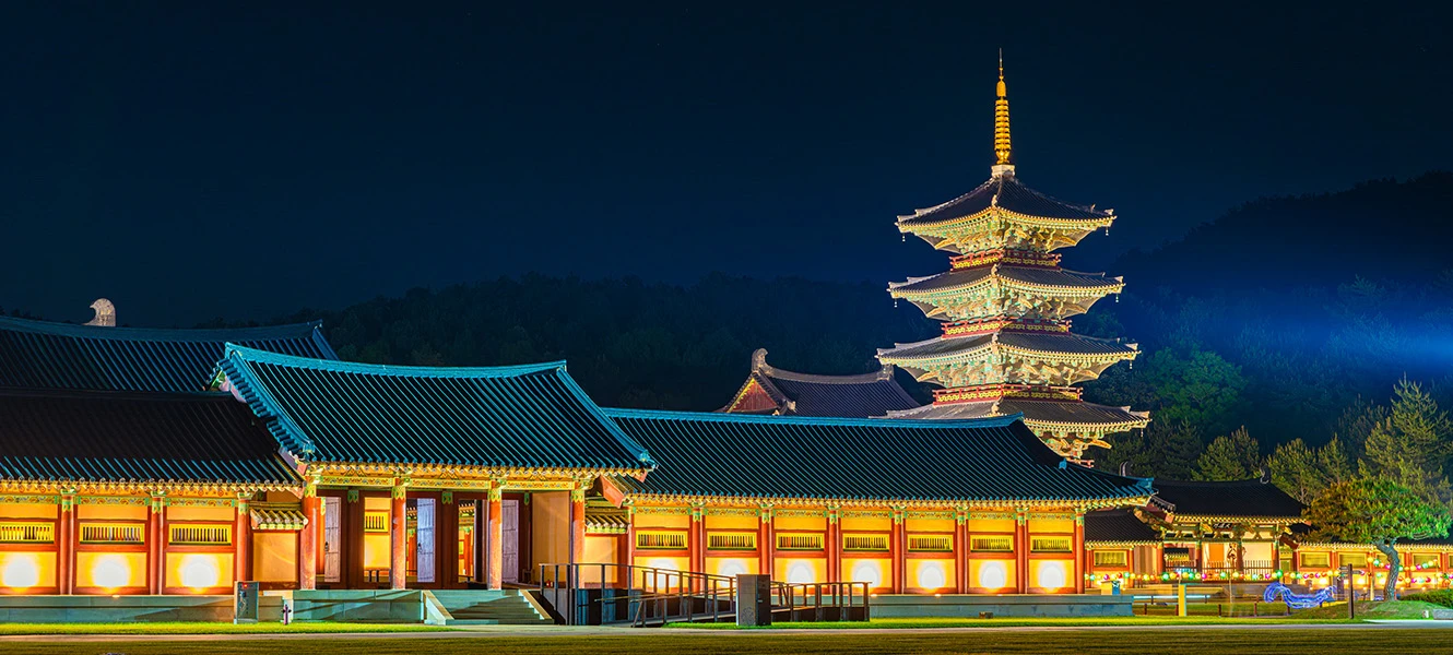 능사 전각과 오층 목탑이 조명으로 밝혀진 푸른 밤의 백제문화단지 야경
