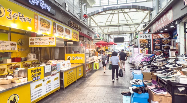 노란 간판 음식점과 신발 가게가 늘어선 외동전통시장 아케이드 통로를 사람들이 오가는 모습
