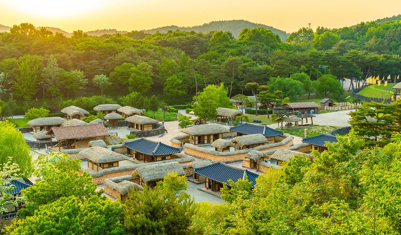 초록 숲에 둘러싸인 백제문화단지 하남위례성 한옥 전각들이 해질녘 햇살에 물든 전경