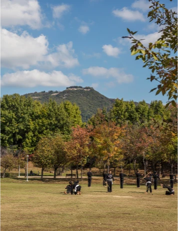 멀리 산봉우리가 보이는 넓은 잔디 공원에서 사람들이 여유롭게 쉬는 가을 풍경