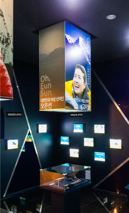 오은선 등 한국 여성 산악인을 소개하는 패널과 영상이 설치된 어두운 전시실