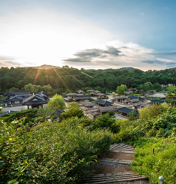 해질녘 산자락 아래 기와집들이 모여 있는 한옥 마을 전경과 내려가는 돌계단 길