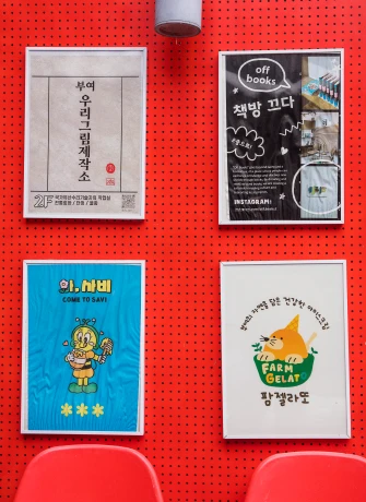 빨간 벽에 부여 우리그린제작소와 책방 포스터, 팜젤라또 안내 액자가 나란히 걸린 모습