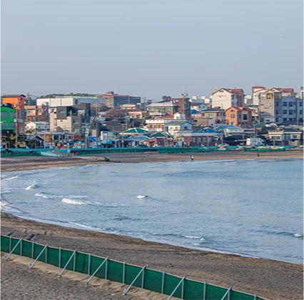 활처럼 휜 백사장과 잔잔한 파도, 그 뒤로 옹기종기 들어선 어촌 마을 전경
