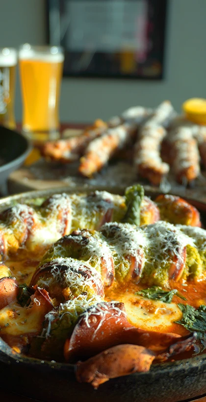 토마토 소스에 치즈를 얹은 속초 통오징어 커틀릿 요리와 뒤편의 맥주잔이 어우러진 한 상