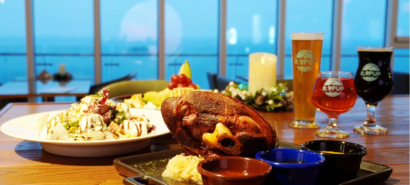 통유리 너머 바다가 보이는 R.9PUP에서 학센과 샐러드, 색색의 맥주가 차려진 저녁 식탁