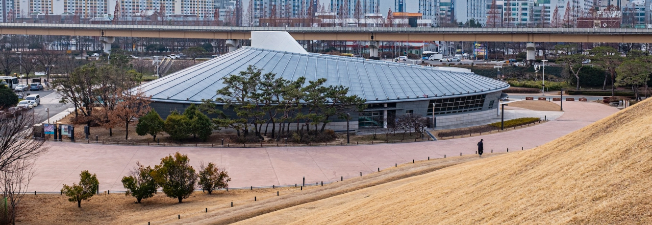 둥근 금속 지붕을 인 대성동고분박물관 건물 전경과 뒤편의 도시 풍경
