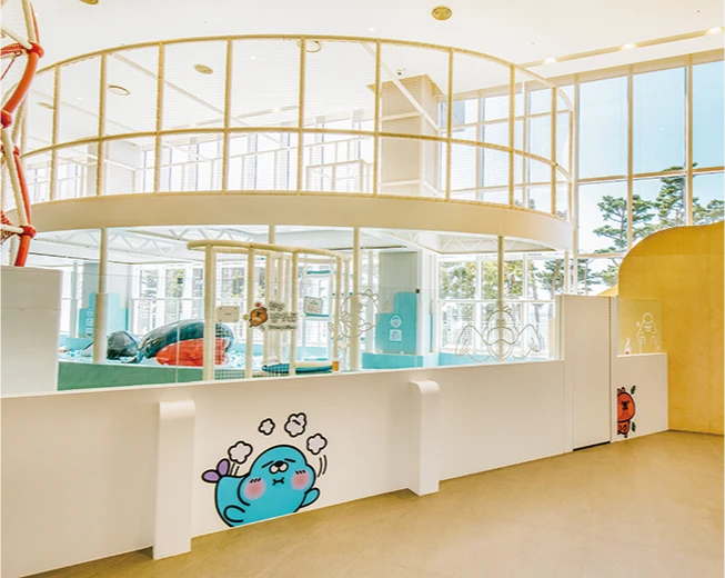 둥근 통창과 흰 난간, 푸른 캐릭터 벽화로 환하게 꾸민 라라키즈어드벤처 내부 전경