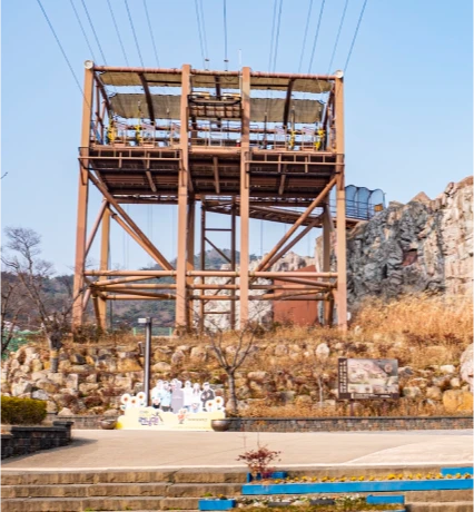 가야테마파크의 높은 철제 구조물 체험시설과 바위 언덕