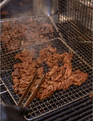석쇠 위에서 집게로 뒤집으며 불맛을 입히는 고추장 불고기 클로즈업