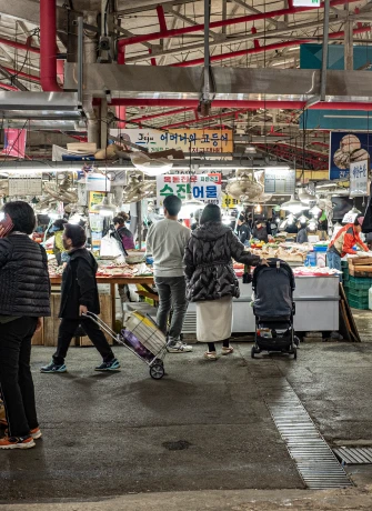 수산어물 간판이 걸린 실내 어물 골목을 장바구니와 유모차를 끌고 오가는 장꾼들