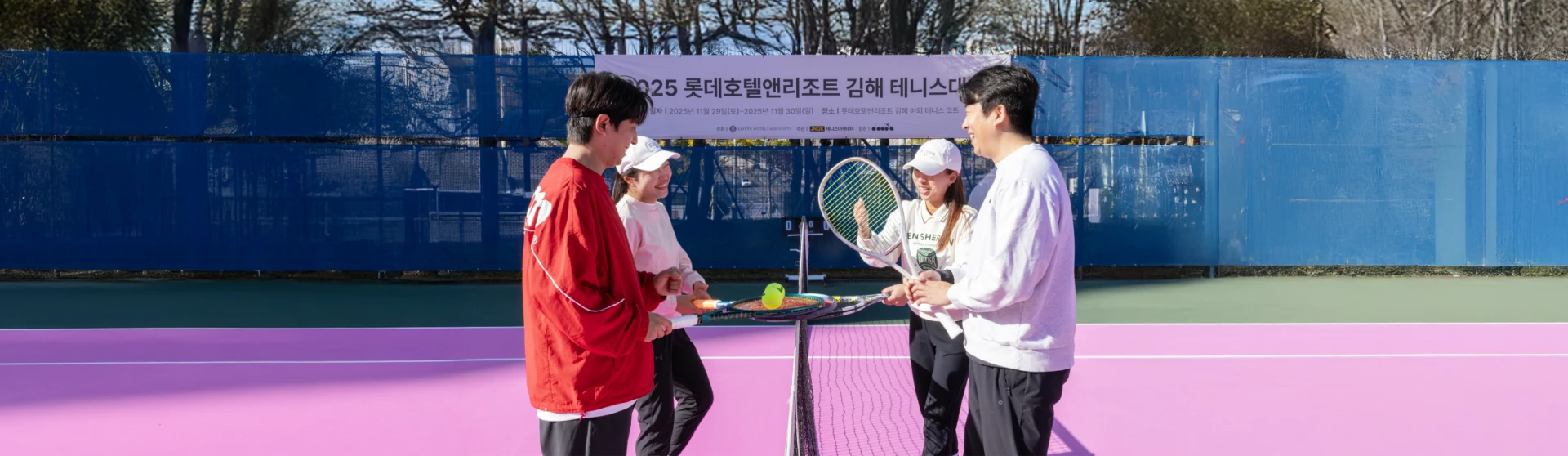 대회 현수막을 배경으로 핑크빛 코트 네트 앞에 모여 라켓을 든 선수들이 인사를 나누는 모습