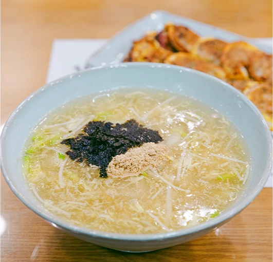 맑은 국물 위에 김가루와 들깨가루를 올린 감자옹심이와 뒤편의 노릇하게 부친 감자전
