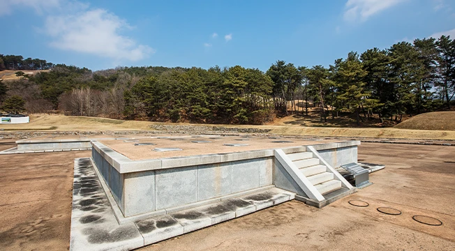 푸른 하늘 아래 돌로 구획된 백제 능산리사지 절터가 넓게 드러난 모습