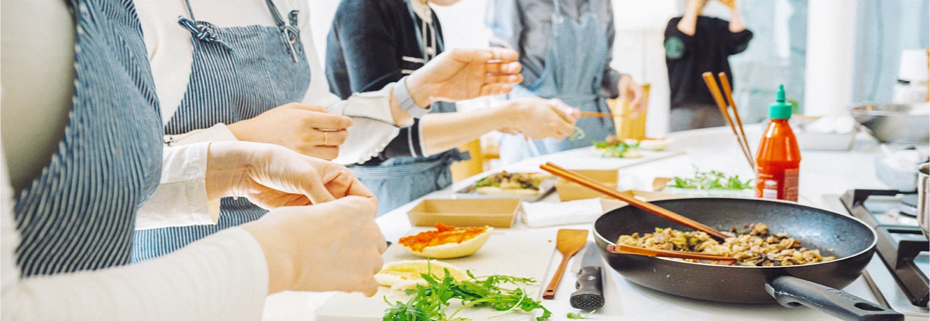 조리대에 둘러선 참가자들이 빵에 소스와 재료를 올리는 과정과 옆의 불고기 팬