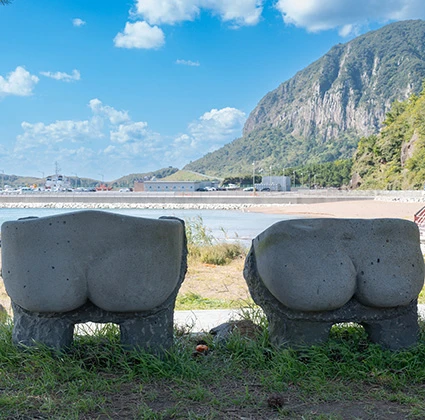 야자수가 늘어선 해변 산책로에 나무 데크와 벤치가 놓인 한적한 풍경